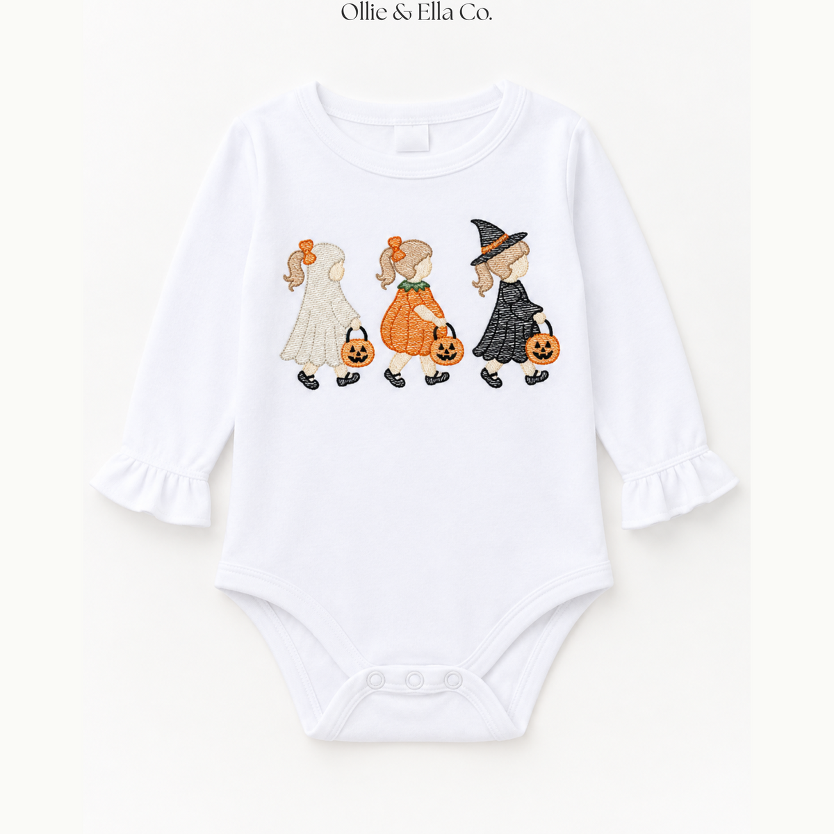 A white long-sleeve baby bodysuit with ruffled cuffs and a graphic print of three children in Halloween costumes walking with pumpkins. The brand name 'Ollie & Ella Co.