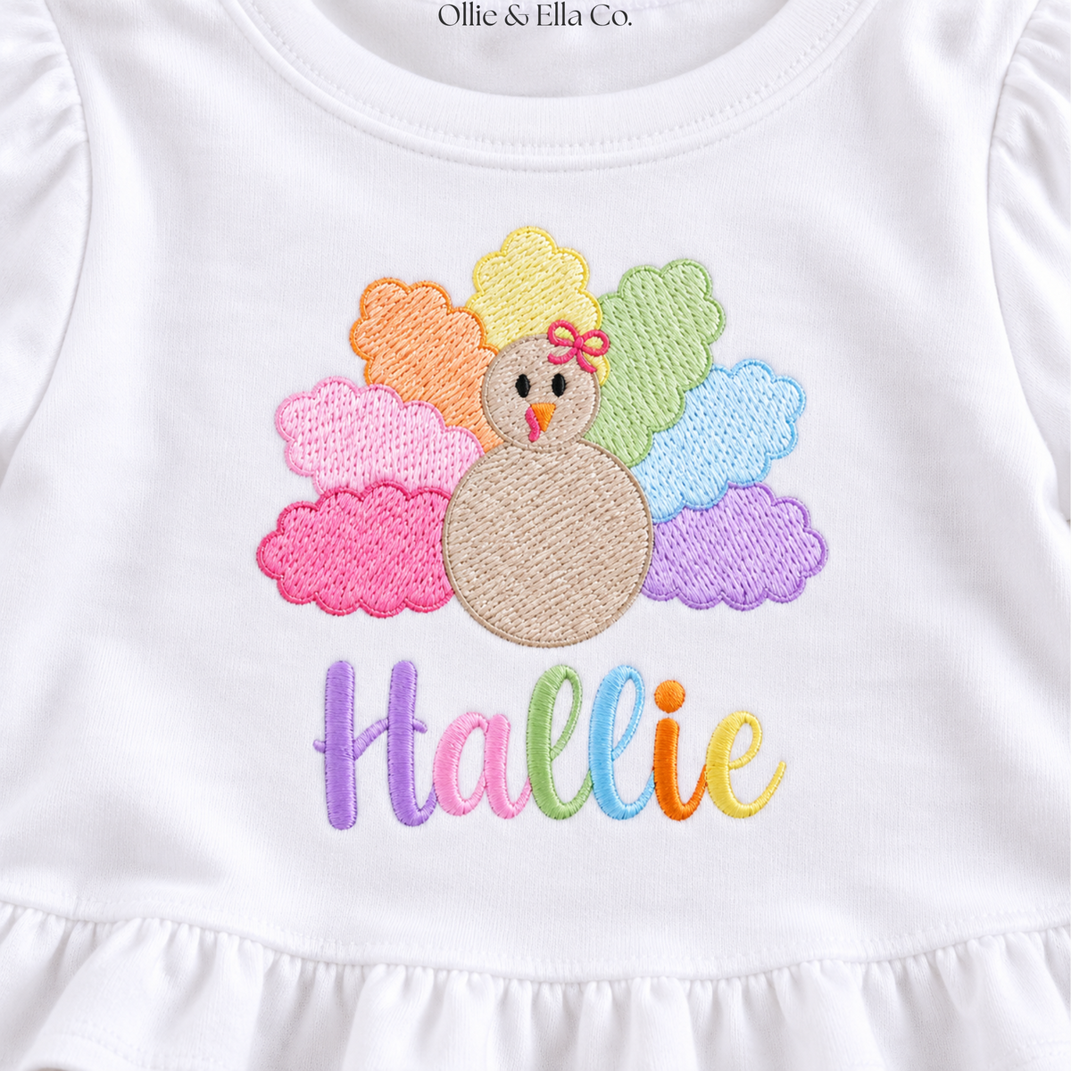 White baby bodysuit featuring an embroidered turkey design with pastel feathers and the name 'Hallie' in colorful script below, from Ollie & Ella Co.